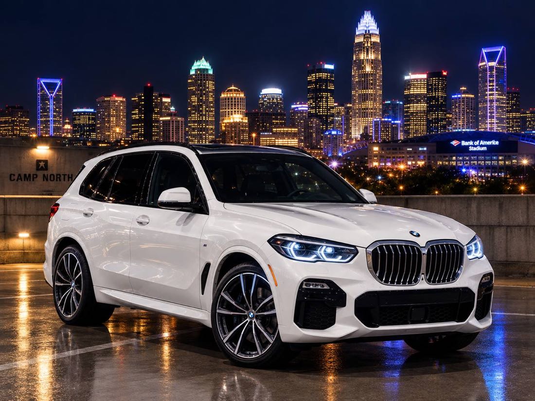 White BMW X5 SUV on a rooftop parking deck with the Charlotte skyline at night